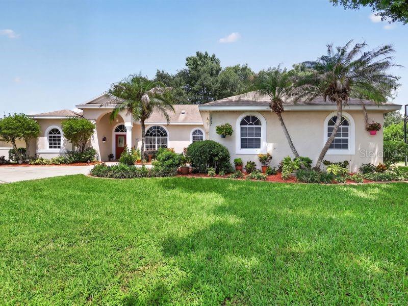 A single-story house with a beige stucco exterior, arched windows, and palm trees in front — 3237 INDIAN TRAIL, EUSTIS, FL