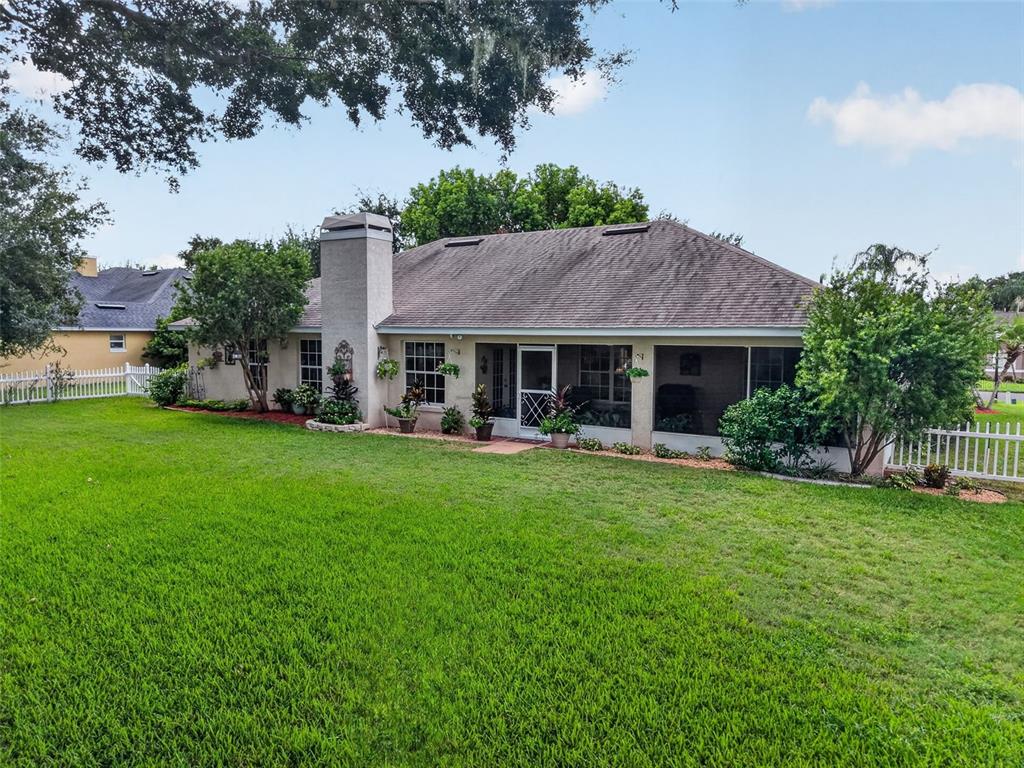 The rear exterior of a single-story house features a screened-in porch and a brick chimney — 3237 INDIAN TRAIL, EUSTIS, FL