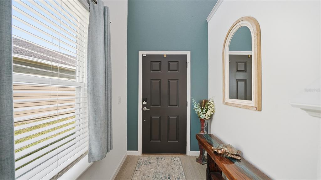 A foyer with a wooden console table, arched mirror, and stairs leading to an open living area — 367 LAKE SINCLAIR STREET, ST AUGUSTINE, FL