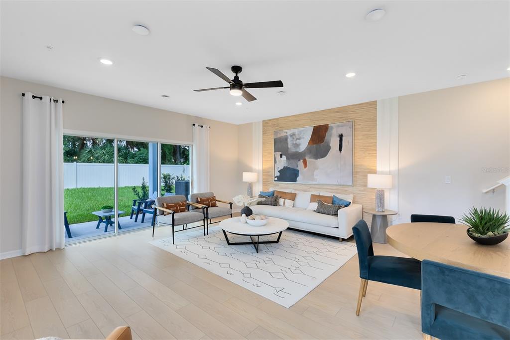 A bright living room features a white sofa, two armchairs, a rug, and sliding glass doors — 4417 JETTY LANE NE, PALM BAY, FL