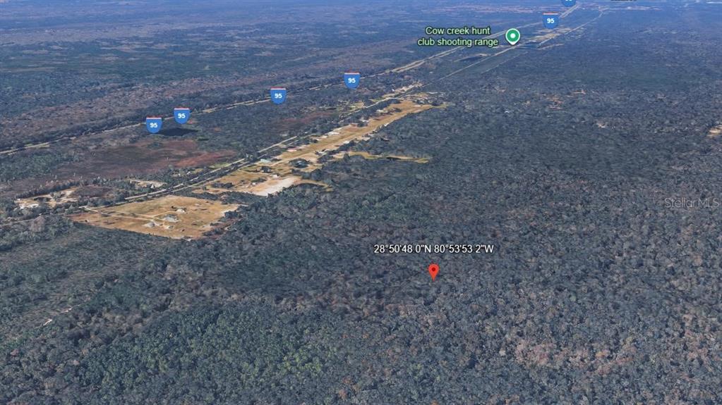 An aerial view shows a forested area with a nearby highway and shooting range — MAYTOWN RD, OAK HILL, FL
