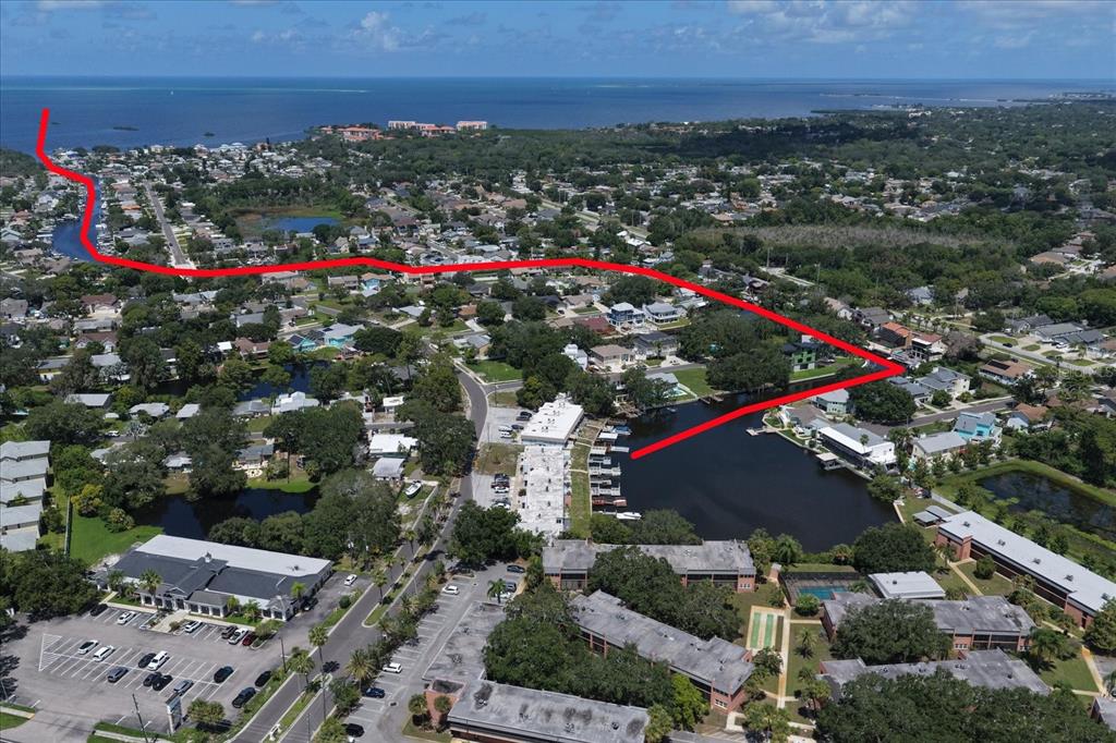 An aerial view shows a waterfront residential complex with boat slips along a canal — 599 WESTWINDS DRIVE UNIT 9, PALM HARBOR, FL