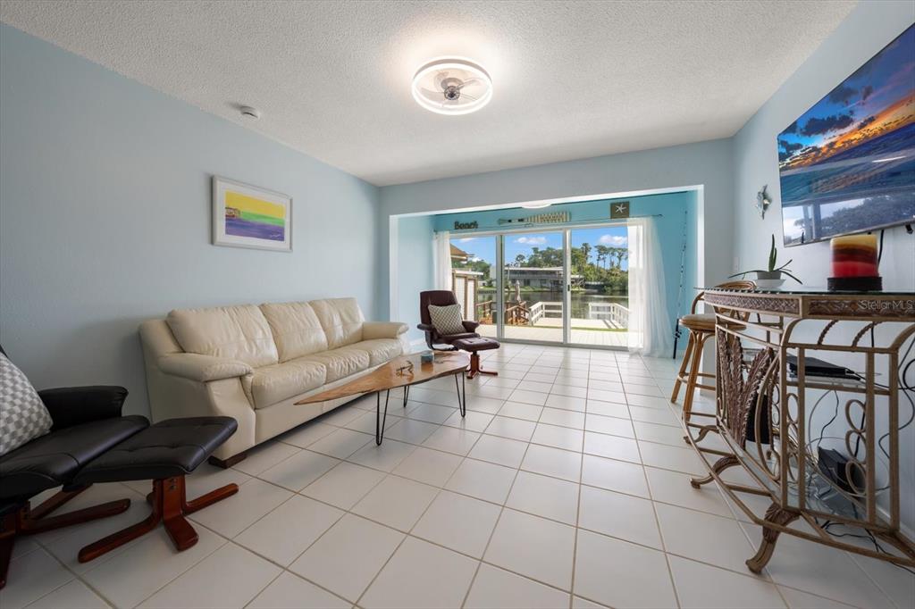 The exterior of a single-story residential building features a sliding glass door and wooden deck — 599 WESTWINDS DRIVE UNIT 9, PALM HARBOR, FL