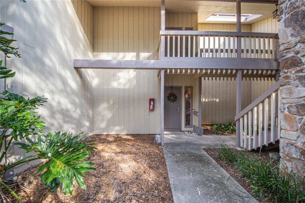An exterior view of a multi-story building entrance with a concrete walkway and wooden railings — 163 PALM VIEW COURT UNIT 3483/4, HAINES CITY, FL