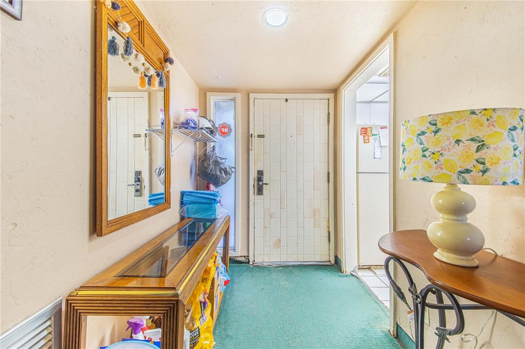 An entryway features a green carpet, a wooden console table with a mirror, and a lamp — 163 PALM VIEW COURT UNIT 3483/4, HAINES CITY, FL