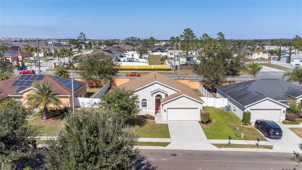An aerial view shows a suburban neighborhood with single-family homes, driveways, and a paved street — 518 HIGHLAND MEADOWS STREET, DAVENPORT, FL