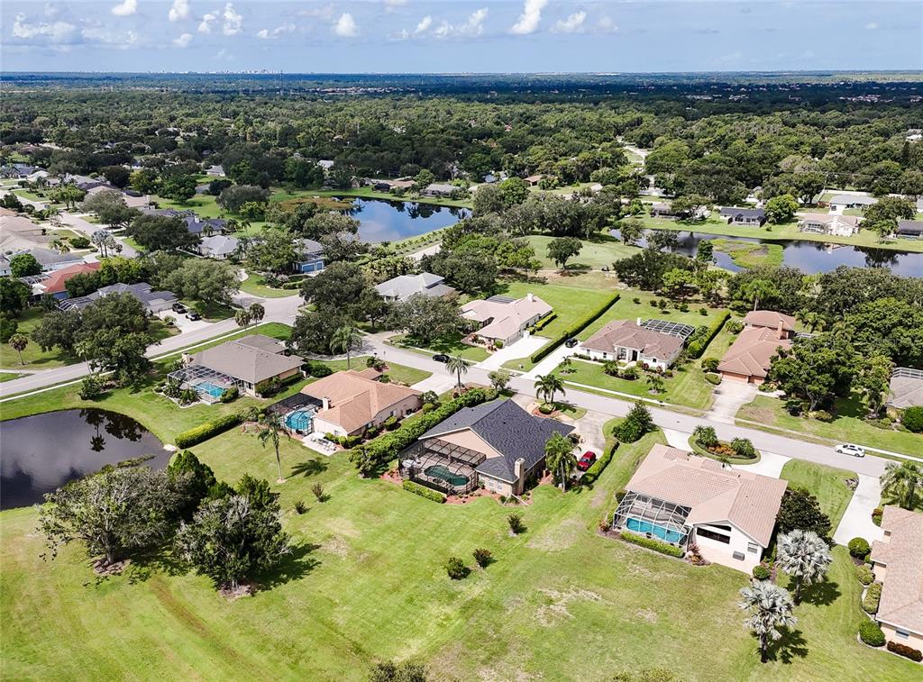 An aerial view shows several suburban houses with swimming pools surrounded by lawns and ponds — 6213 GLEN ABBEY LANE, BRADENTON, FL
