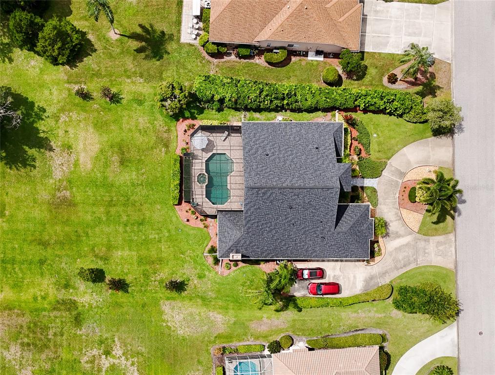 An aerial view shows a house with a pool enclosure, driveway, and surrounding lawn — 6213 GLEN ABBEY LANE, BRADENTON, FL
