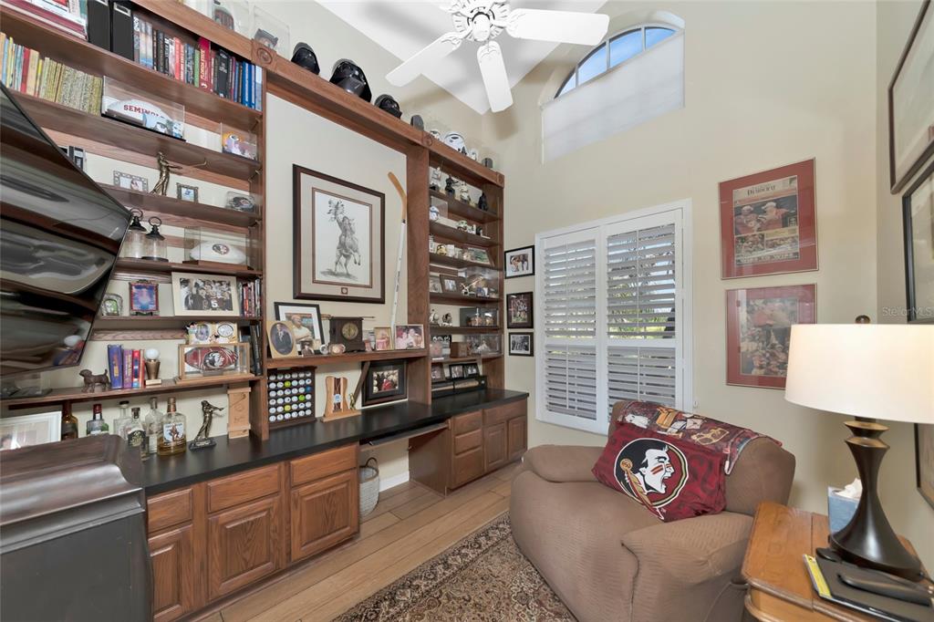 A home office features built-in wooden shelving, a ceiling fan, and a comfortable armchair — 6213 GLEN ABBEY LANE, BRADENTON, FL