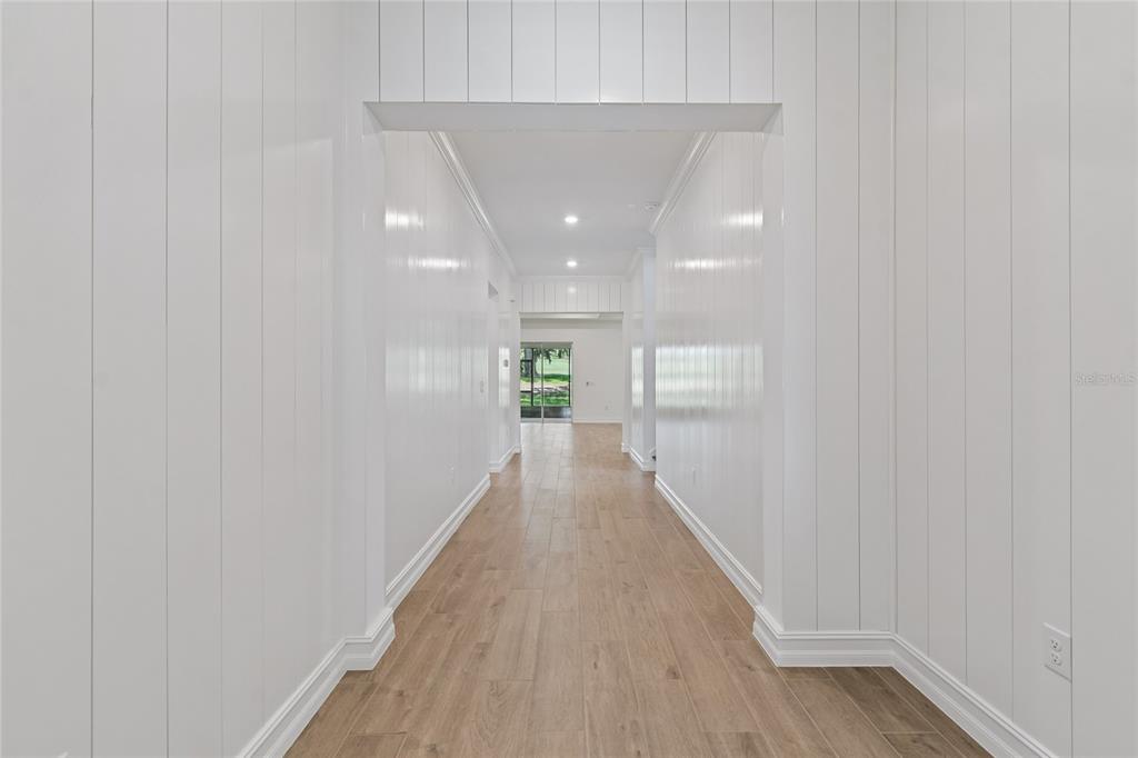 A long hallway features white vertical paneled walls and light wood-look flooring — 4794 SOUTHERN VALLEY LOOP, BROOKSVILLE, FL