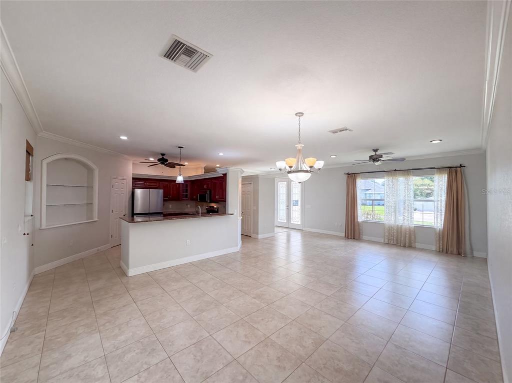 An open-concept living area features tile flooring, a kitchen with dark cabinets, and a chandelier — 4625 GARDEN AVENUE, SEBRING, FL