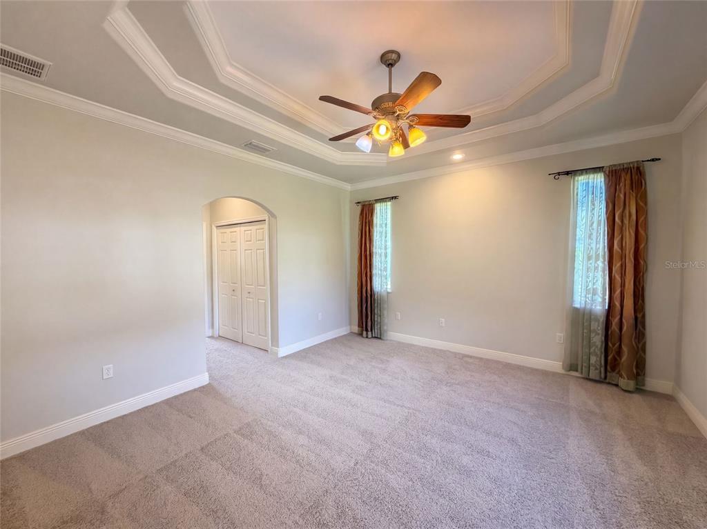 A bedroom features a tray ceiling, a ceiling fan, carpeted flooring, and two windows with curtains — 4625 GARDEN AVENUE, SEBRING, FL
