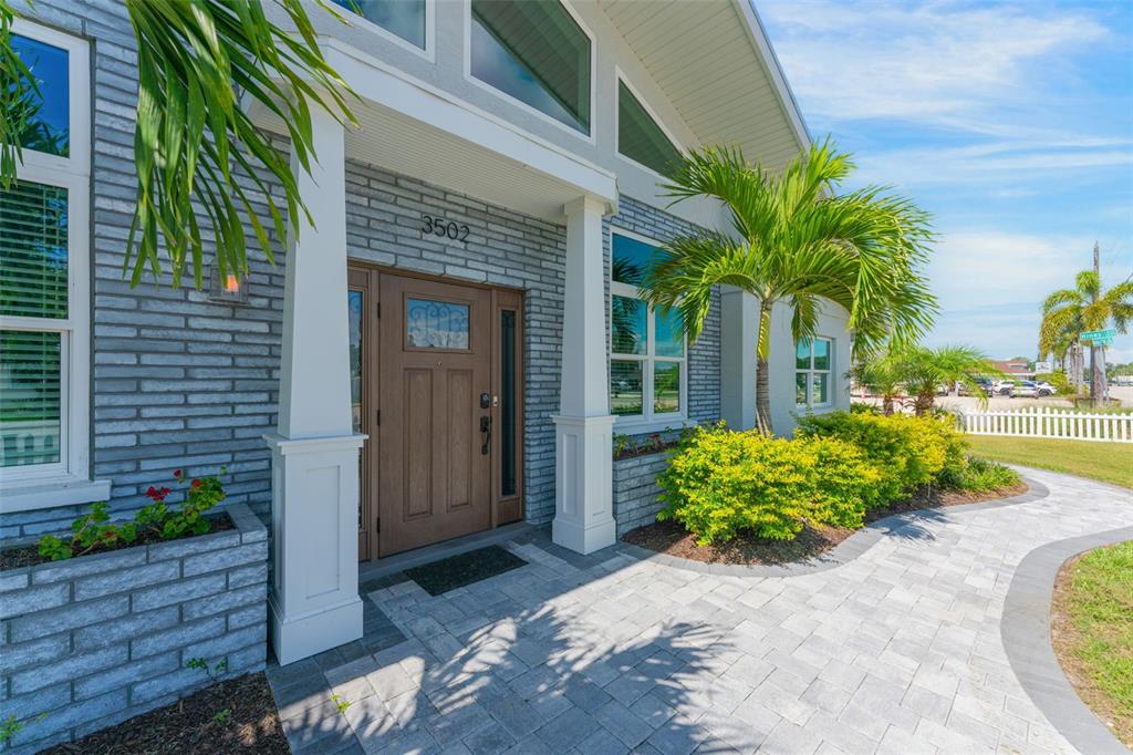 A gray brick house exterior features a brown front door, white columns, and palm trees — 3502 BAHIA VISTA STREET, SARASOTA, FL