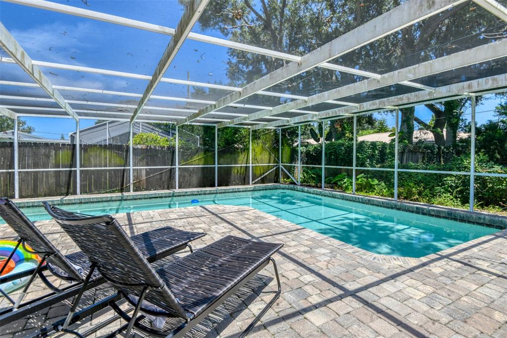 A screened-in swimming pool with a paver deck and two lounge chairs in a backyard — 15 SEA PARK DRIVE, ST AUGUSTINE, FL