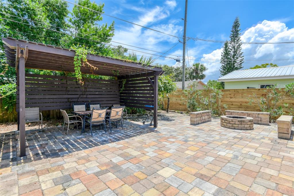 A backyard patio features a wooden pergola, dining set, fire pit, and stone pavers — 15 SEA PARK DRIVE, ST AUGUSTINE, FL