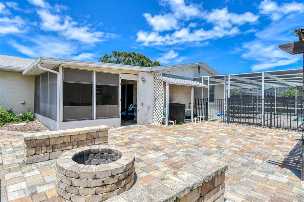 A backyard patio features a stone fire pit, paver flooring, a screened porch, and pool enclosure — 15 SEA PARK DRIVE, ST AUGUSTINE, FL