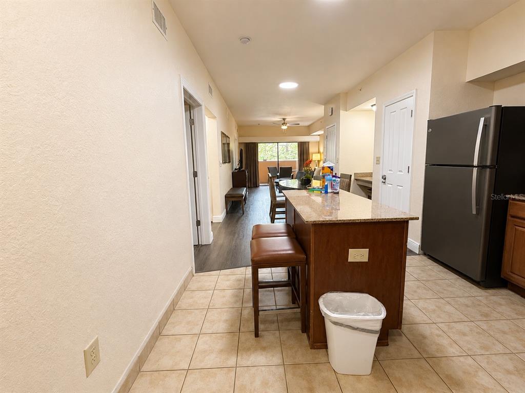 A kitchen with a granite island and bar stools opens into a living area — 12539 FLORIDAYS RESORT DRIVE UNIT 208D, ORLANDO, FL