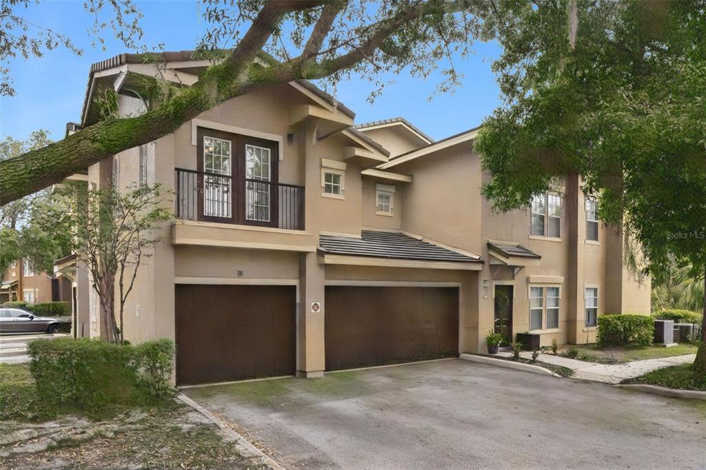 A two-story tan building with black garage doors and a second-floor balcony — 143 VILLA DI ESTE TERRACE UNIT 209, LAKE MARY, FL