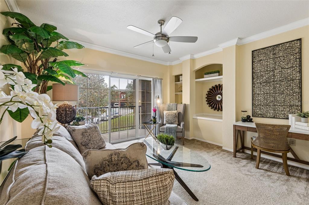 A living room with beige carpet, yellow walls, a ceiling fan, and sliding glass doors — 143 VILLA DI ESTE TERRACE UNIT 209, LAKE MARY, FL