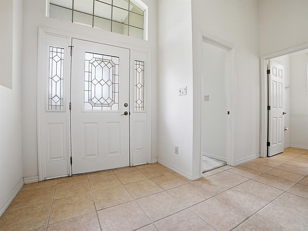 A tiled entryway features a white front door with sidelights, a transom window, and doorways — 5106 CHANTICLEER DRIVE, LEESBURG, FL