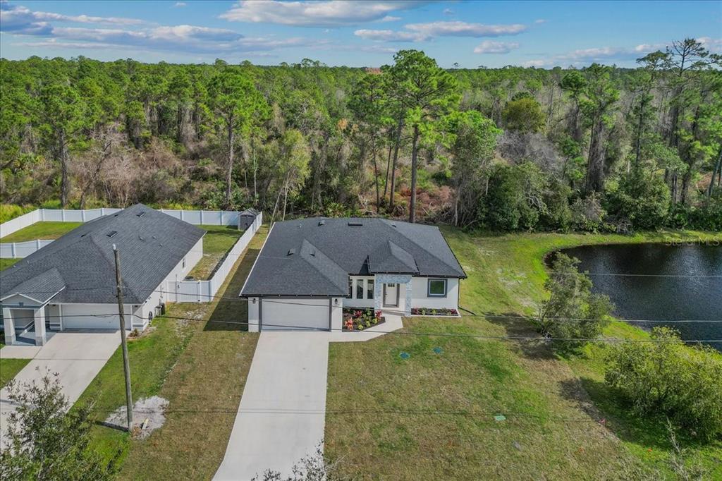 A single-story house with a white stucco exterior, a two-car garage, and stone entryway accents — 2875 E SLATER DRIVE, DELTONA, FL