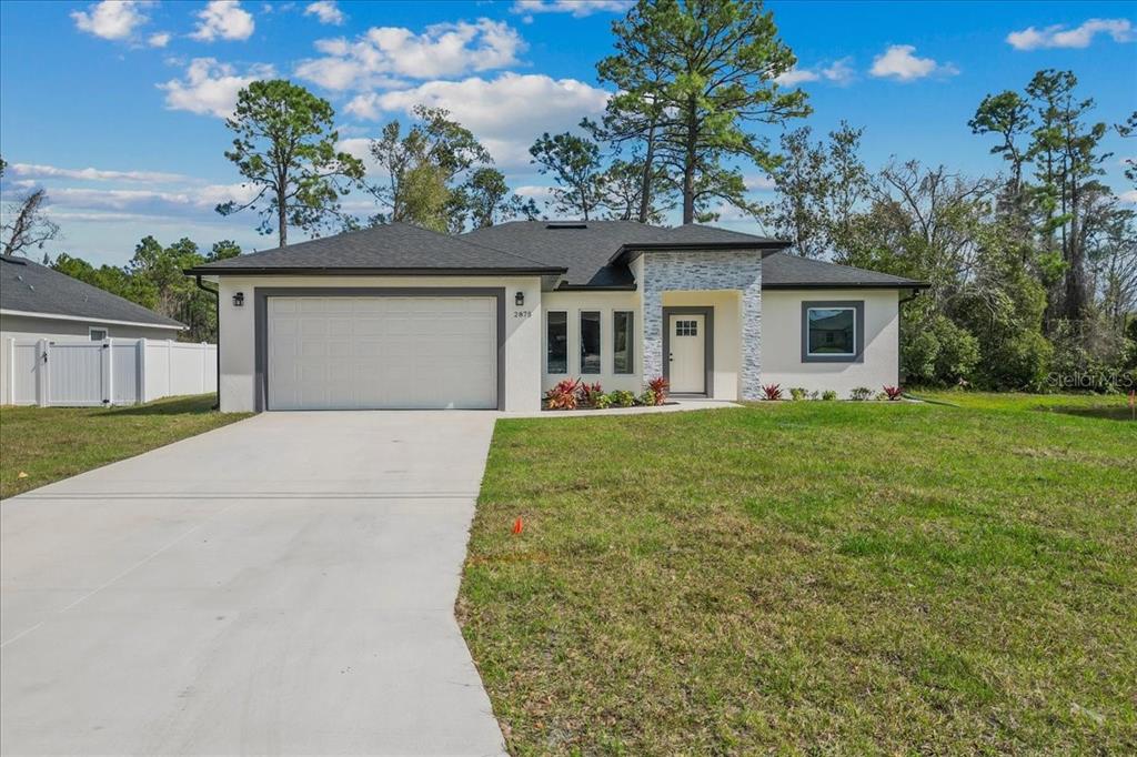 A single-story house with a white exterior, a two-car garage, and a stone-accented entryway — 2875 E SLATER DRIVE, DELTONA, FL