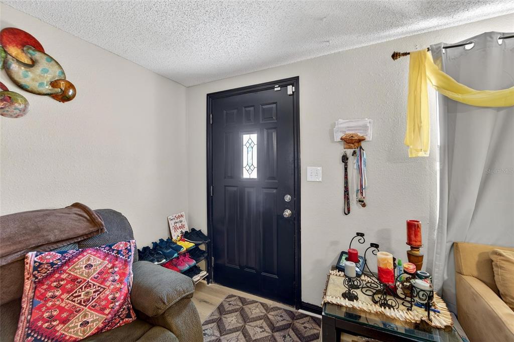 An entryway features a black front door, a shoe rack, and a side table — 15821 ADOBE DRIVE, HUDSON, FL