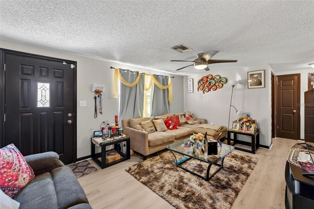 A living room features light wood flooring, a tan sectional sofa, and a glass coffee table — 15821 ADOBE DRIVE, HUDSON, FL