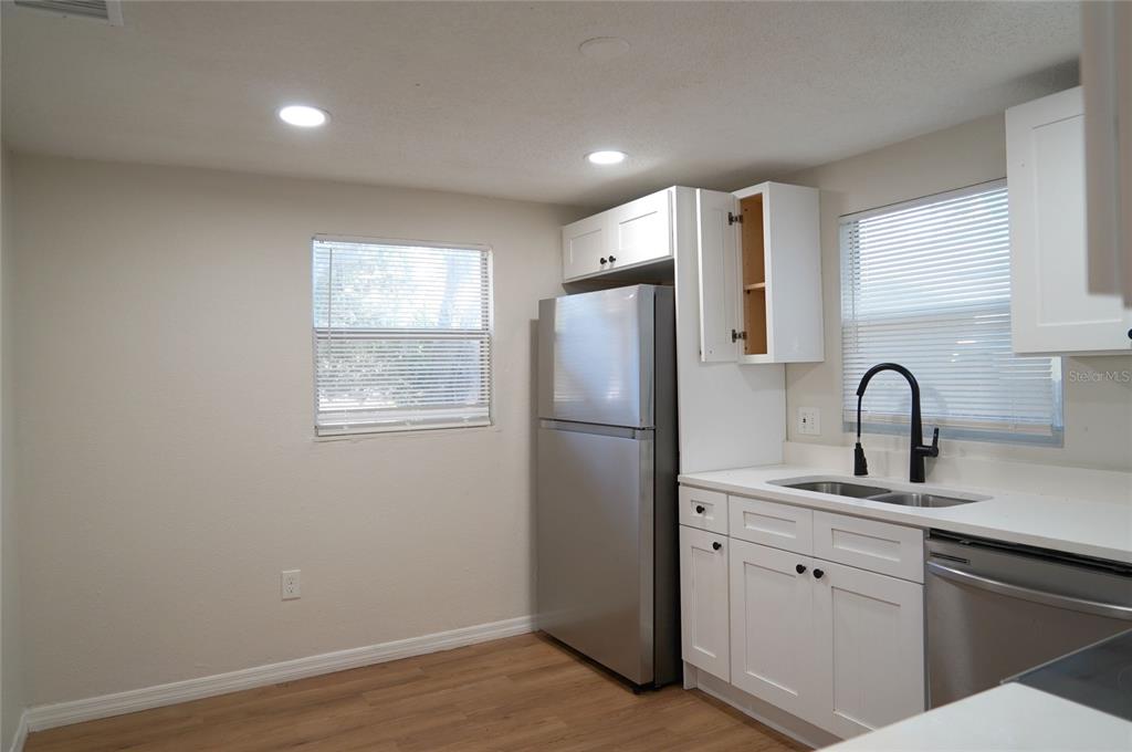 A kitchen features white cabinets, stainless steel appliances, a black range hood, and white countertops — 4509 N 29TH STREET, TAMPA, FL