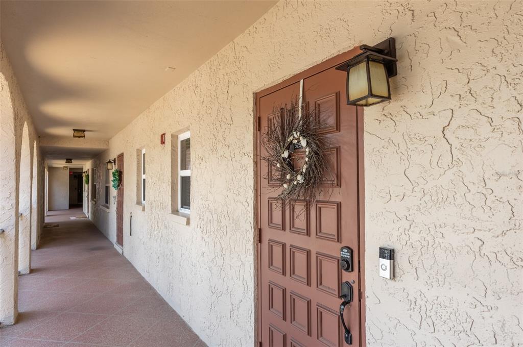 A brown front door with a wreath and keypad lock sits along an outdoor hallway — 9700 STARKEY ROAD UNIT 325, SEMINOLE, FL