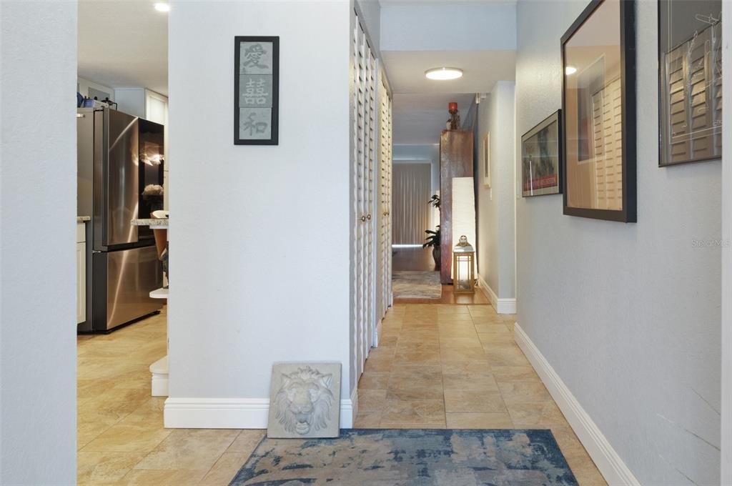 A hallway with tile flooring leads toward a kitchen and a living area with blinds — 9700 STARKEY ROAD UNIT 325, SEMINOLE, FL