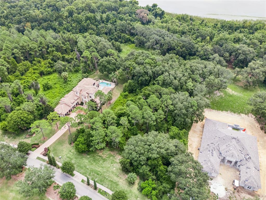 An aerial view shows a large house with a pool and a nearby construction site — 17119 ETRUSCAN LANE, MONTVERDE, FL