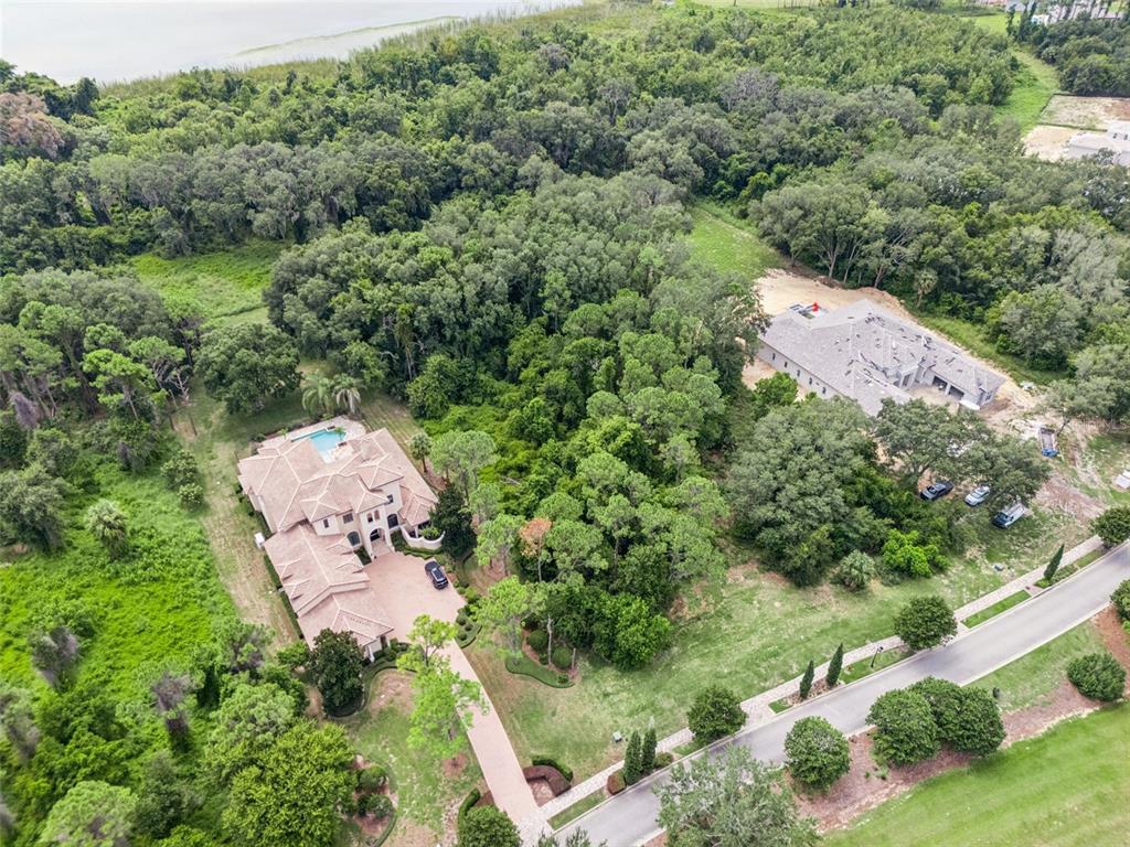 An aerial view shows a large house with a pool and a nearby construction site — 17119 ETRUSCAN LANE, MONTVERDE, FL