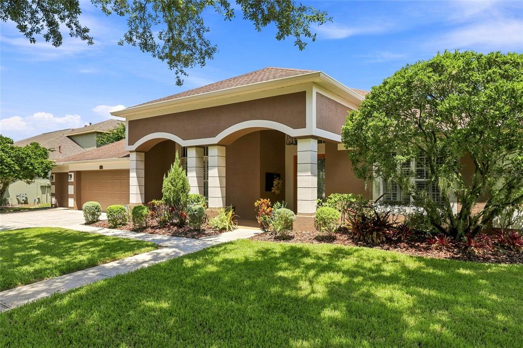 A single-story house with a brown stucco exterior, arched entryway, and a two-car garage — 8310 SUMMER GROVE ROAD, TAMPA, FL