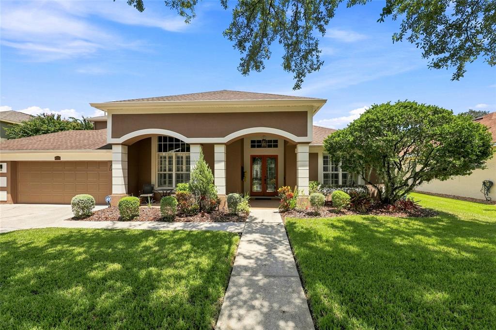 A single-story house with a brown exterior, arched entryway, and a concrete walkway — 8310 SUMMER GROVE ROAD, TAMPA, FL