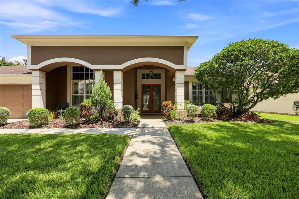 A single-story house with a brown stucco facade, arched entryway, and a concrete walkway — 8310 SUMMER GROVE ROAD, TAMPA, FL