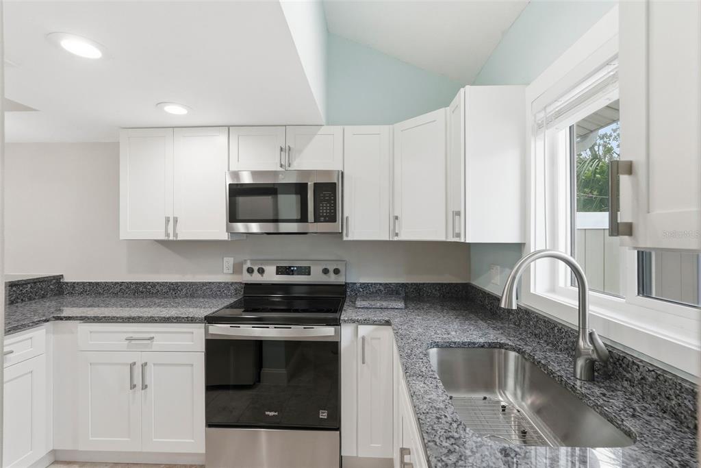 A kitchen with white cabinets, granite countertops, stainless steel appliances, and a stainless steel sink — 3120 BEACH BOULEVARD S UNIT 1, ST PETERSBURG, FL