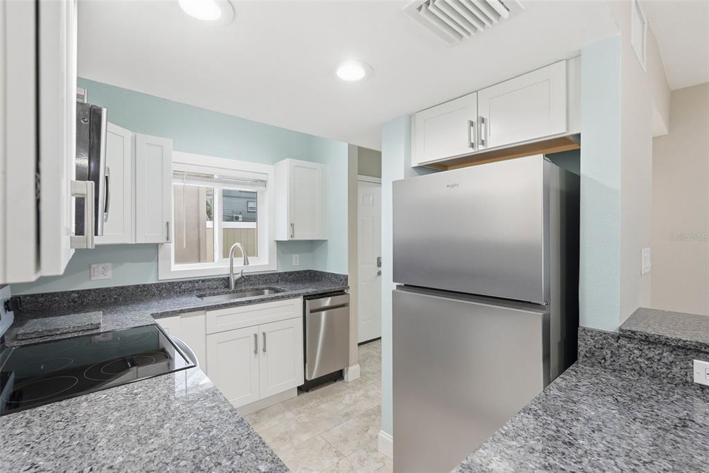 A kitchen features white cabinets, granite countertops, stainless steel appliances, and light blue walls — 3120 BEACH BOULEVARD S UNIT 1, ST PETERSBURG, FL
