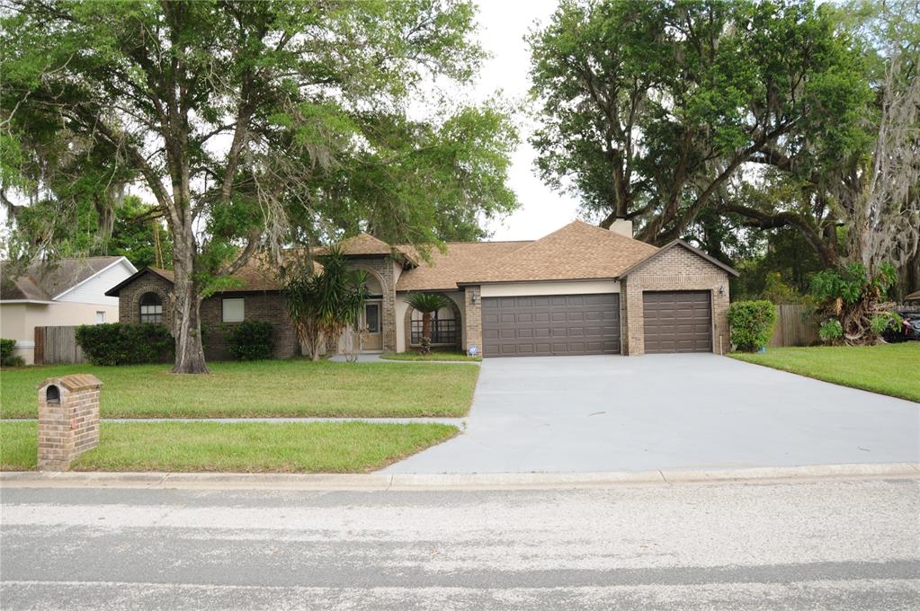 A single-story brick house with a three-car garage and a large front lawn — 2106 WHITLOCK PLACE, DOVER, FL
