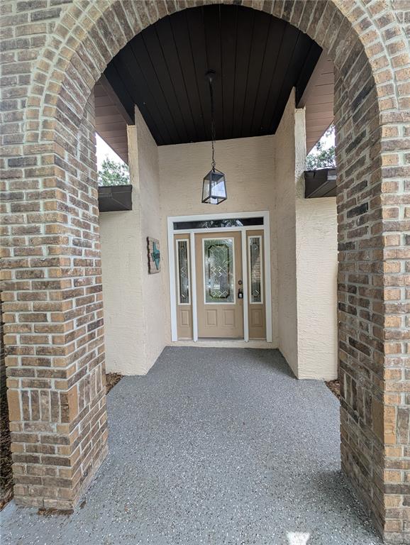 A front entryway features a brick archway, a tan door with sidelights, and a hanging lantern — 2106 WHITLOCK PLACE, DOVER, FL
