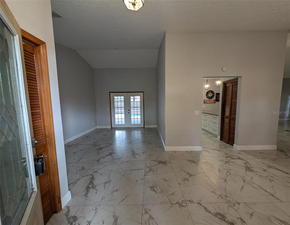 An entryway leads to a living area with marble-look tile floors and glass patio doors — 2106 WHITLOCK PLACE, DOVER, FL