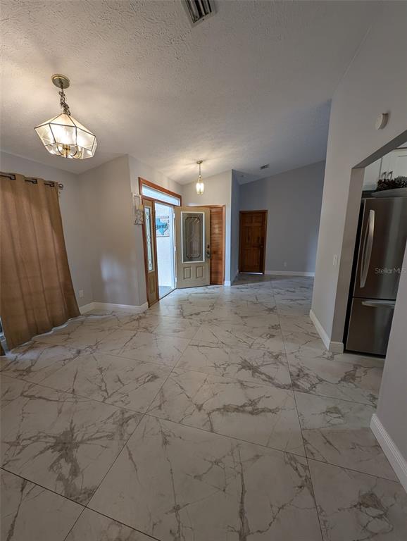 A room with large white marble-patterned floor tiles, a pendant light, and an entryway door — 2106 WHITLOCK PLACE, DOVER, FL