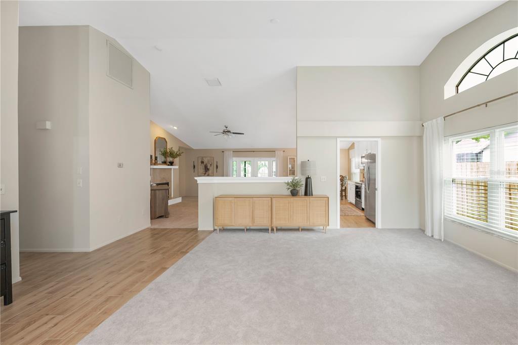 A living room features carpeted flooring, a sectional sofa, a television, and a dark dresser — 12004 STEPPINGSTONE BOULEVARD, TAMPA, FL