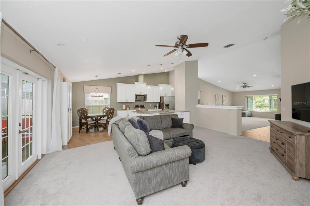 A spacious living room features neutral carpeting, a large gray sectional sofa, and vaulted ceilings — 12004 STEPPINGSTONE BOULEVARD, TAMPA, FL