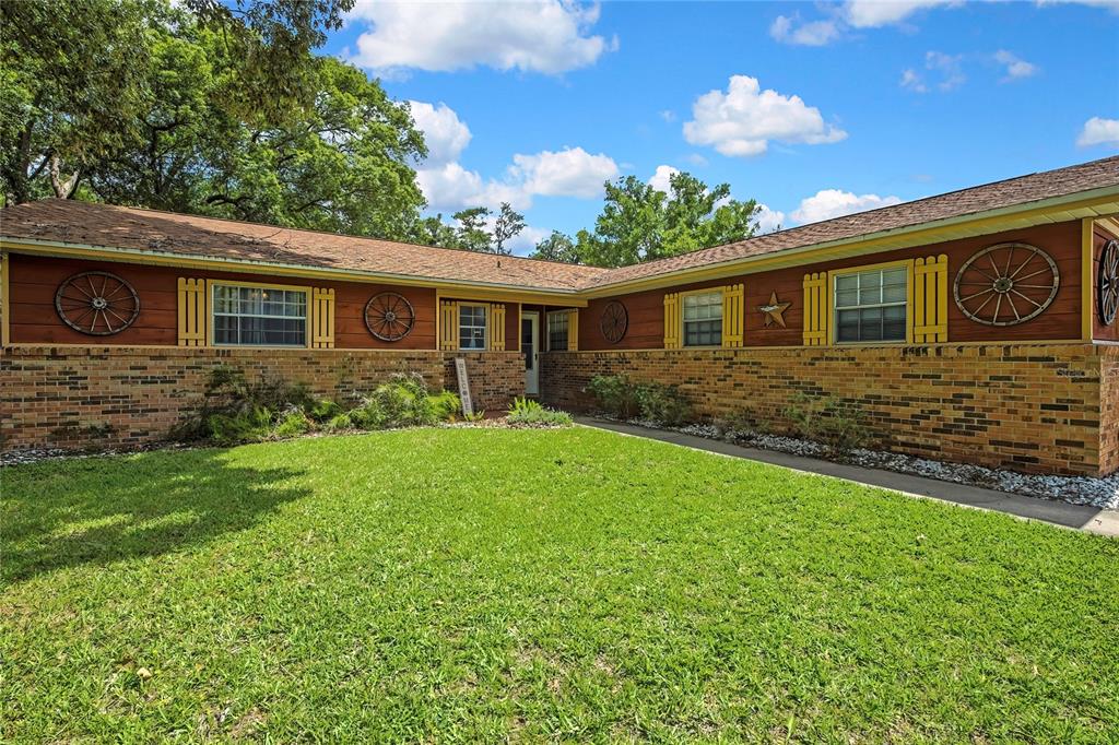 A single-story brick and wood-sided house features wagon wheel decor and yellow window shutters — 1931 SE 39TH STREET, OCALA, FL