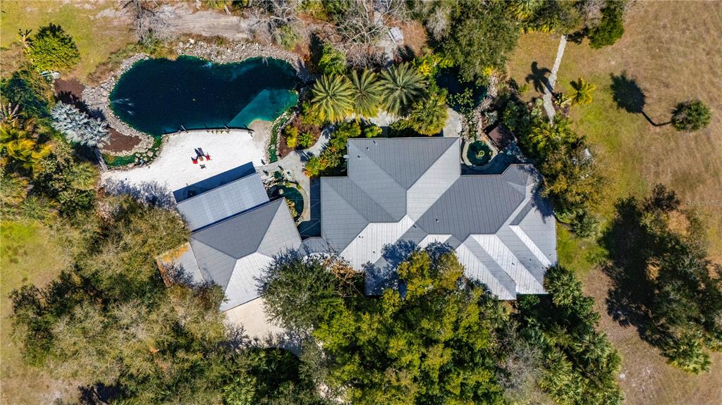 An aerial view shows a house with a metal roof, a pool, and sandy beach — 29505 JONES LOOP ROAD, PUNTA GORDA, FL