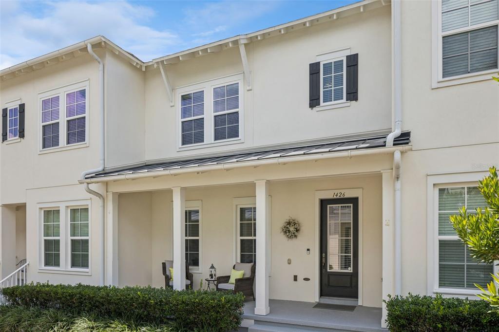 A two-story townhouse exterior with a covered front porch, black shutters, and a dark door — 1426 RESOLUTE STREET, CELEBRATION, FL