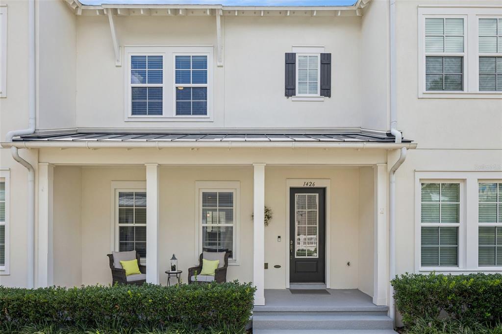 The exterior of a two-story townhouse features a covered front porch with two chairs — 1426 RESOLUTE STREET, CELEBRATION, FL