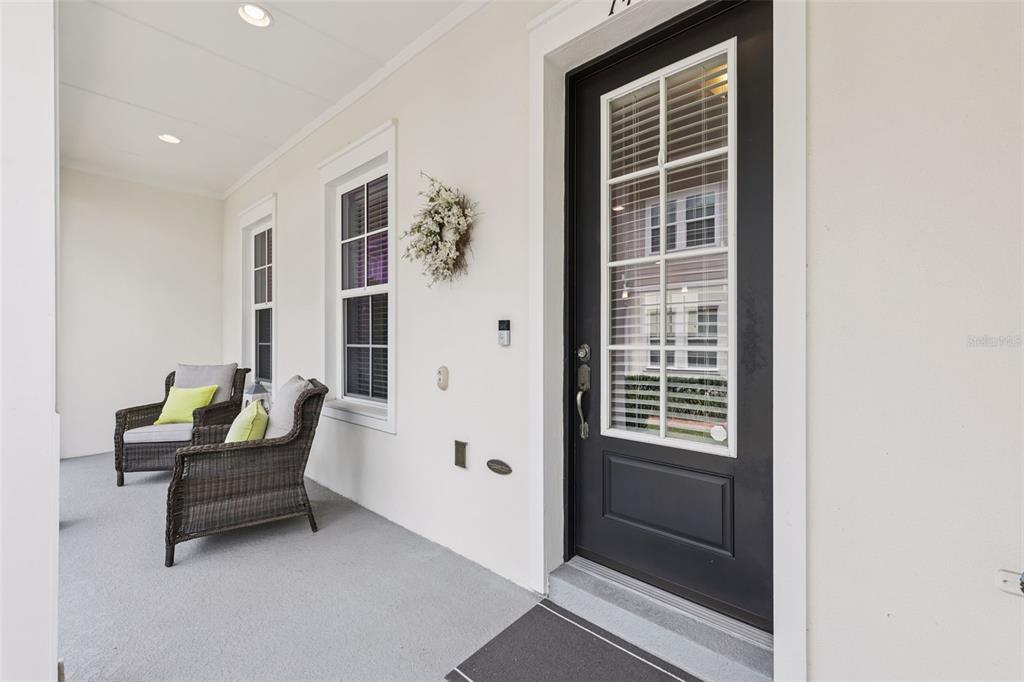A covered front porch features two wicker chairs and a black front door with glass — 1426 RESOLUTE STREET, CELEBRATION, FL