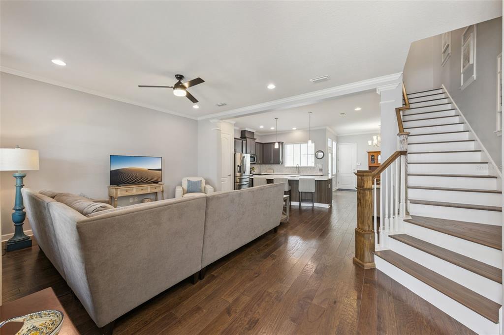 An open-concept living room with a sectional sofa, hardwood floors, and a staircase — 1426 RESOLUTE STREET, CELEBRATION, FL